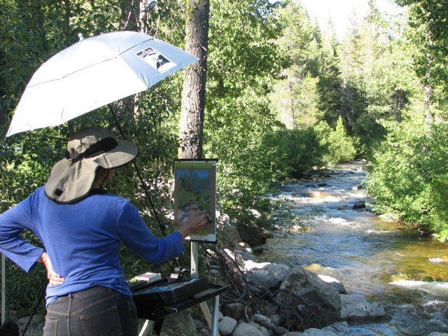 student in the wood with painting easel near stream