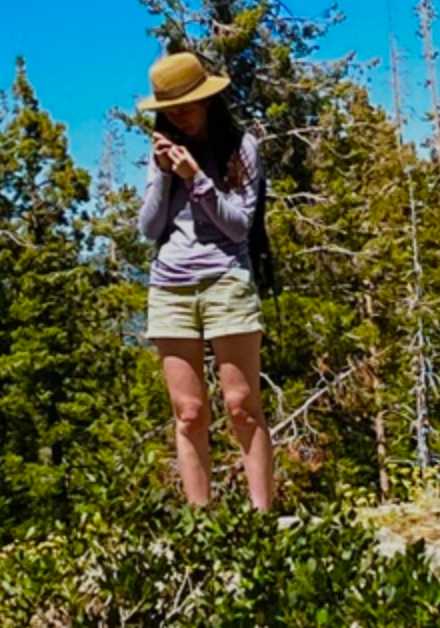 woman wearing hat examining a plant